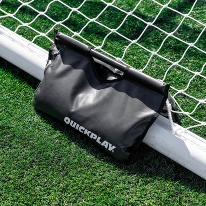 Black sand bag with 'QuickPlay' branding on a soccer goalpost.