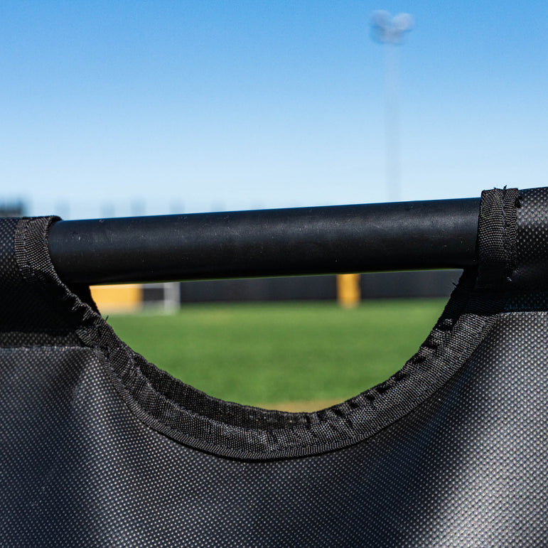 Close-up of a black sand bag with a clear sky and grassy area in the background.