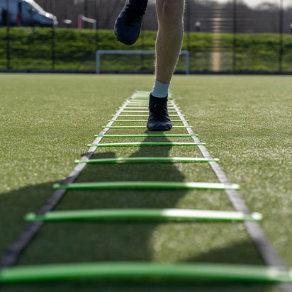 Person using a agility ladder on a sports field