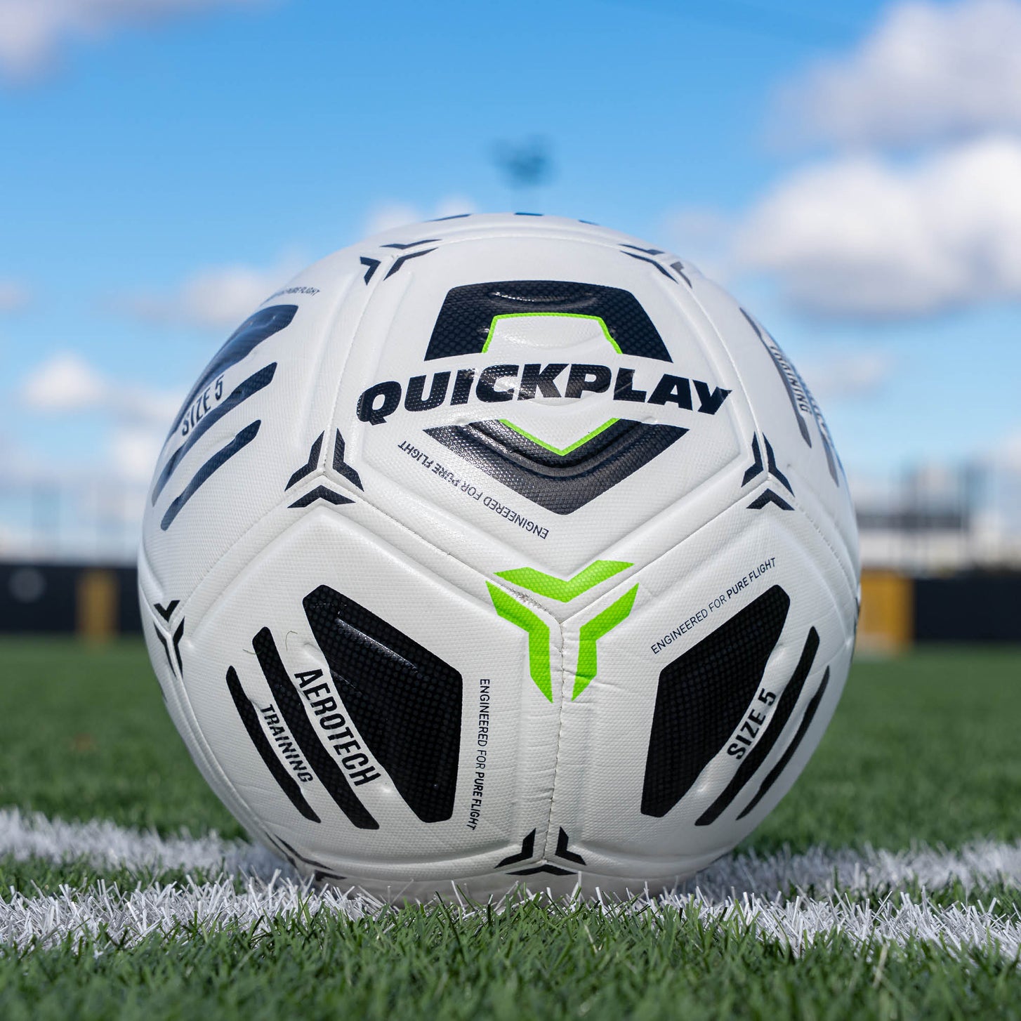 White football with black and green accents on a grass field, featuring the Quickplay brand.