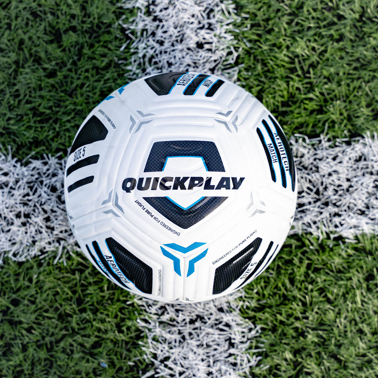 White football with black and blue patterns on a grass field, featuring the 'Quickplay' brand.