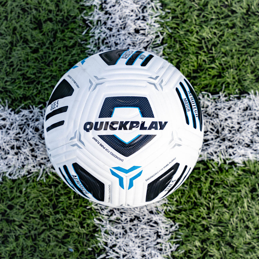 White football with black and blue patterns on a grass field, featuring the 'Quickplay' brand.