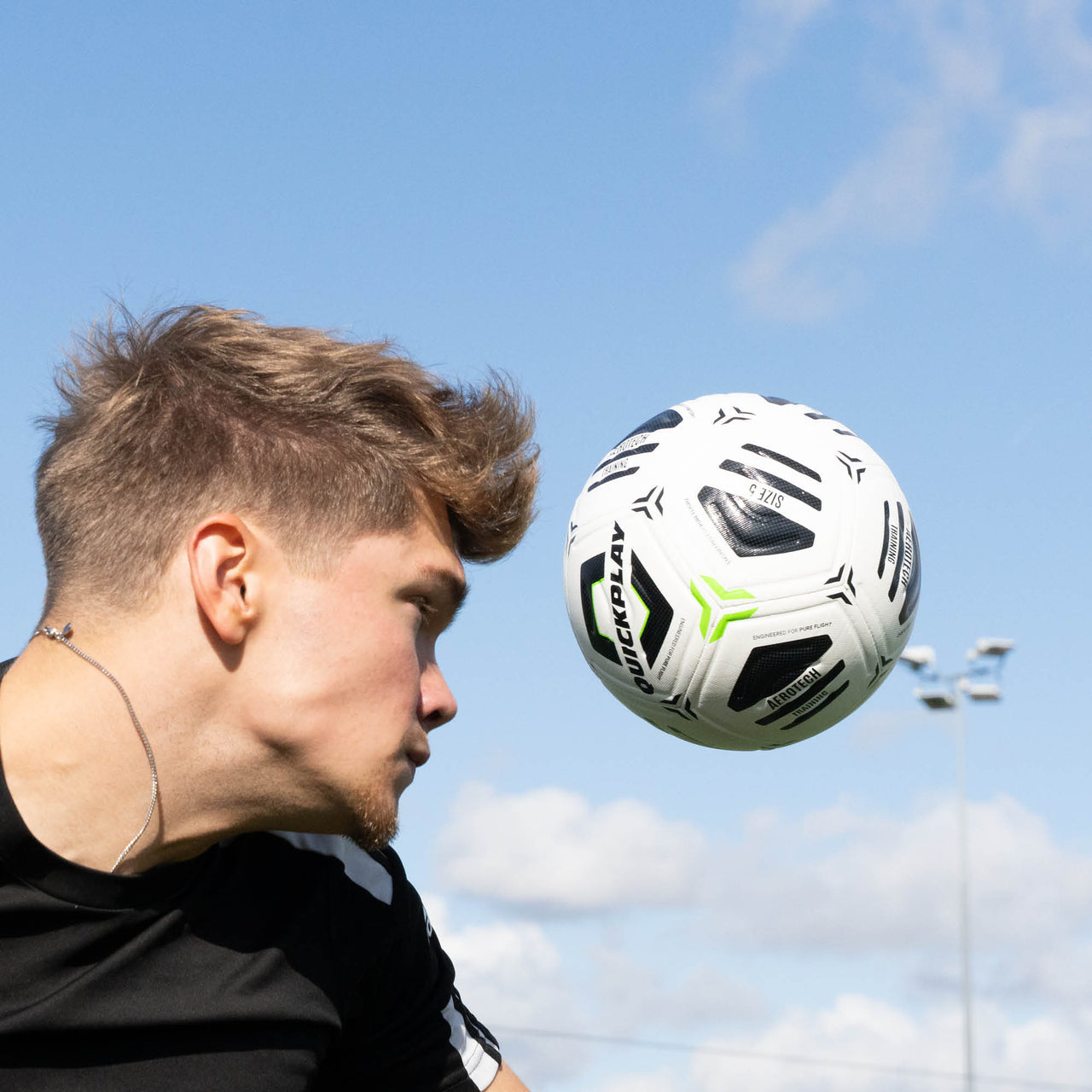 Person heading a football with a clear blue sky in the background