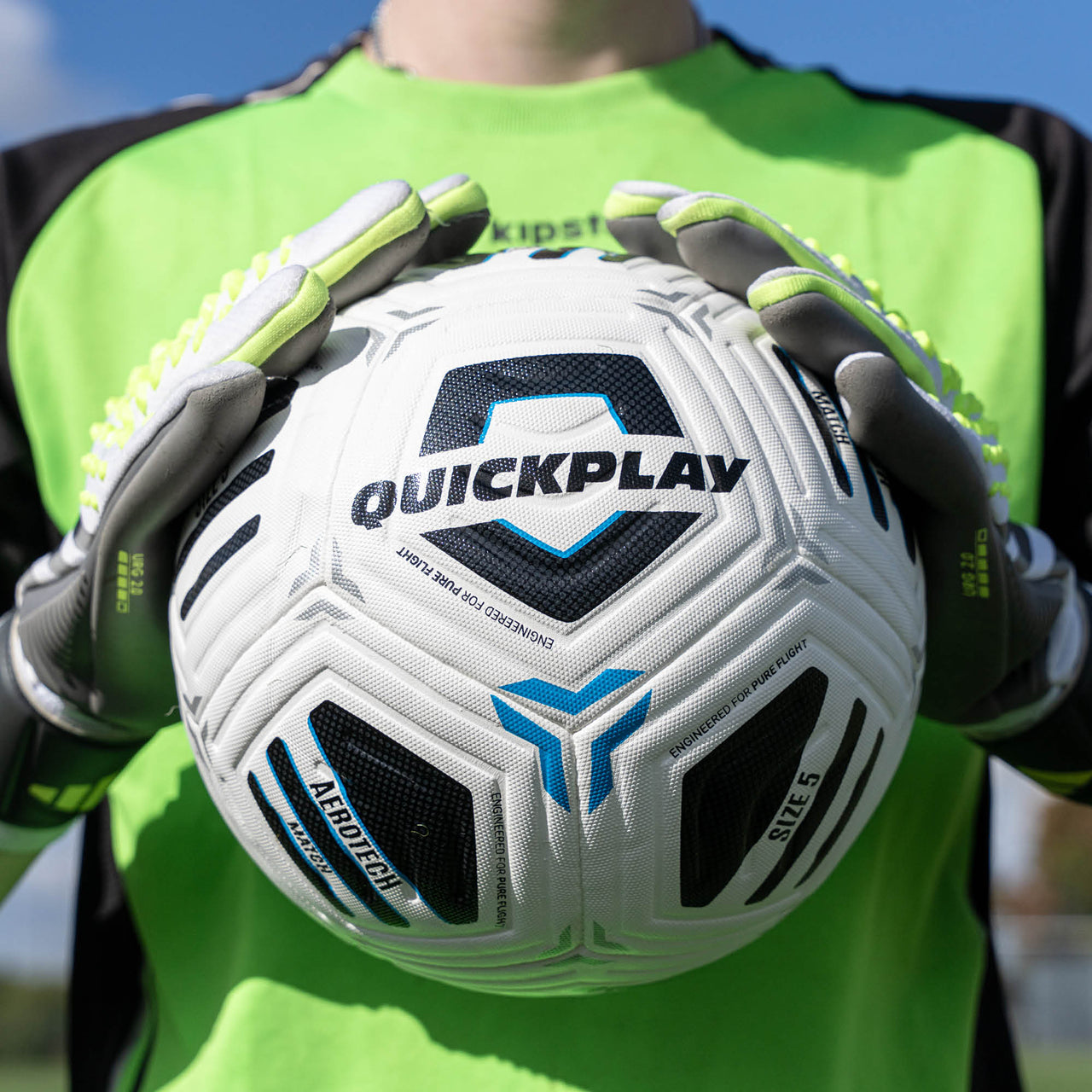 Person holding a Quickplay football with gloves on a clear day