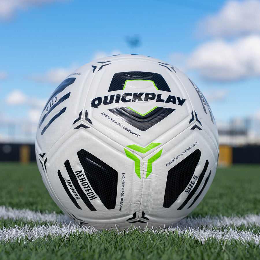 White football with black and green accents on a grass field, featuring the Quickplay brand.