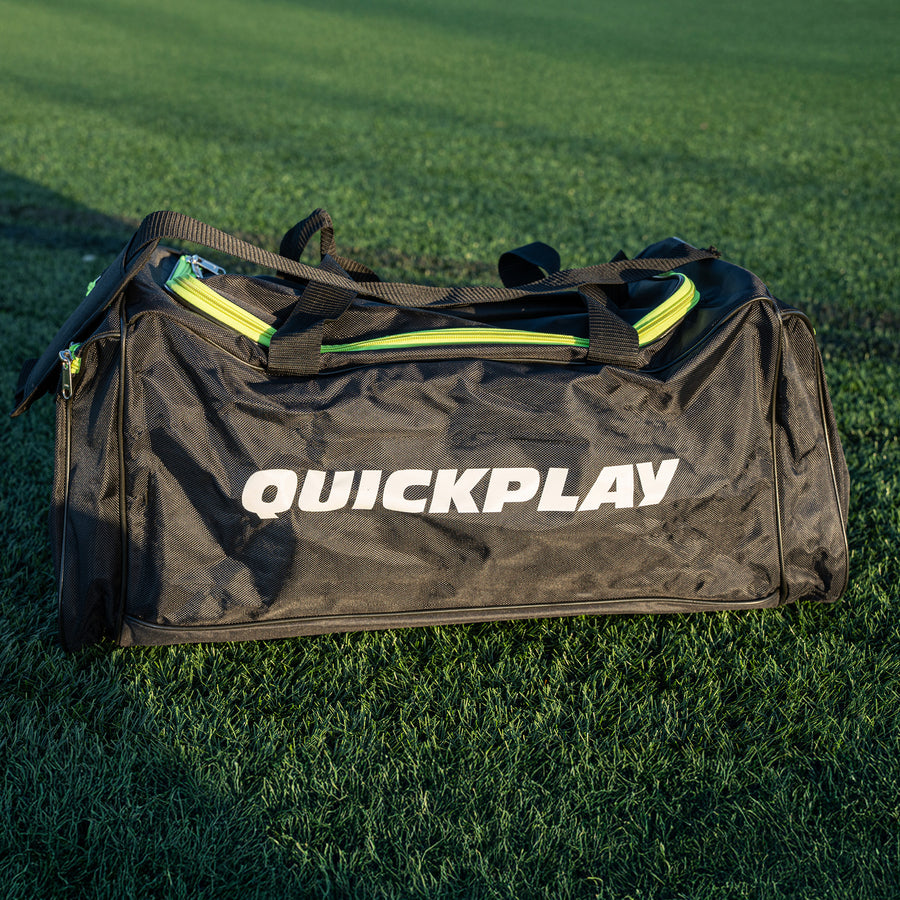 QUICKPLAY Equipment & Kit Bag (M) in black with lime green zips and carry handles, on artificial grass.