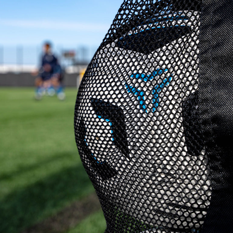 Close-up of a black and football bag with a blurred football field background