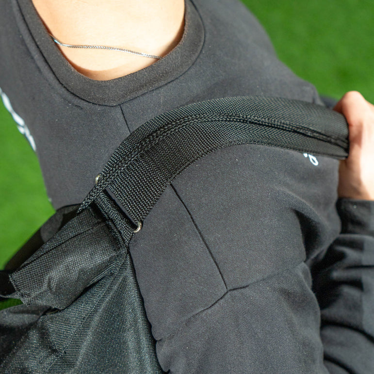 Person wearing a dark gray jacket with a black strap over a green background