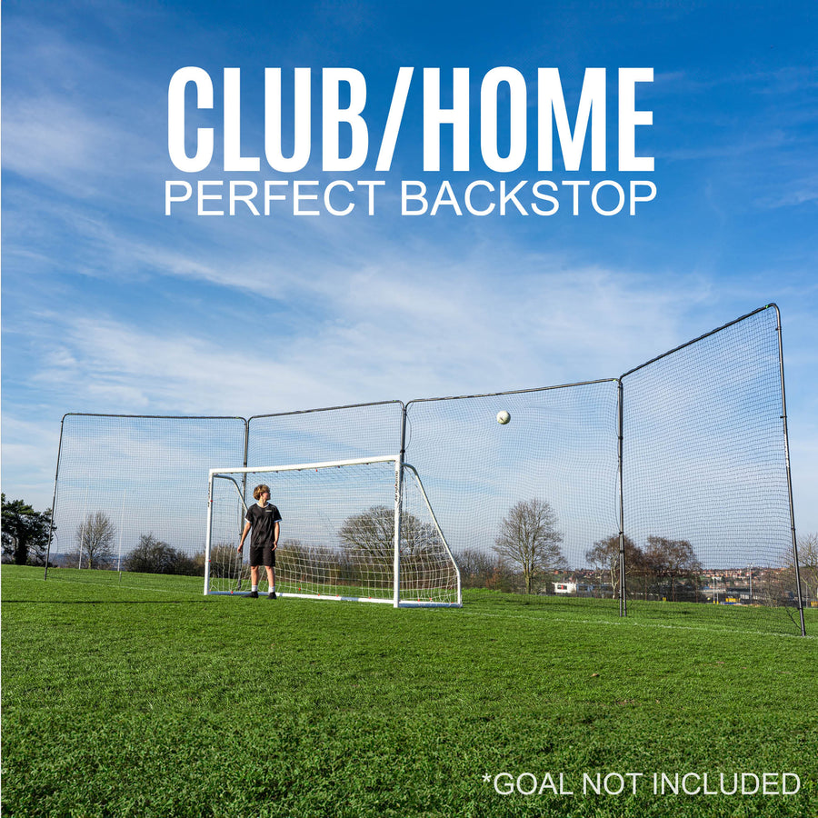 football goal backstop with a barrier net system behind it on a grass field with a clear blue sky.
