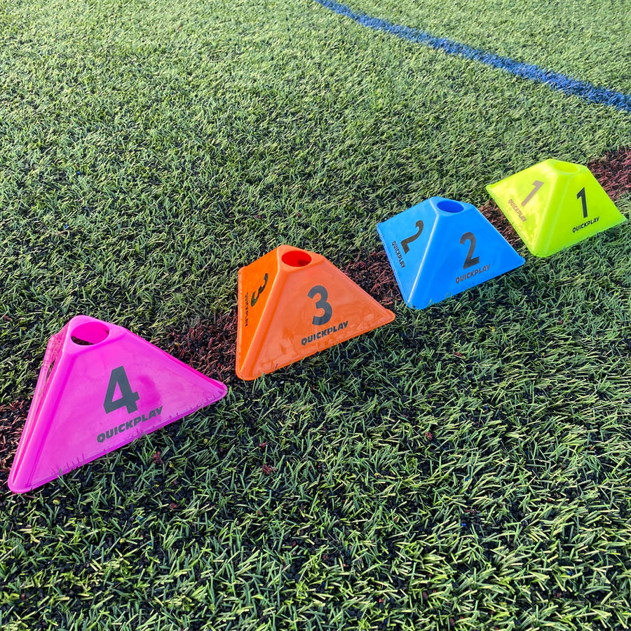 A series of coloured triangular cognitive cones numbered from 1 to 4 placed on a grass surface, likely used for sports training drills.