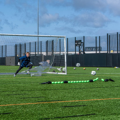 goalkeeper practicing soccer on a field with a goal and QUICKPLAY goalkeeper deflection line.