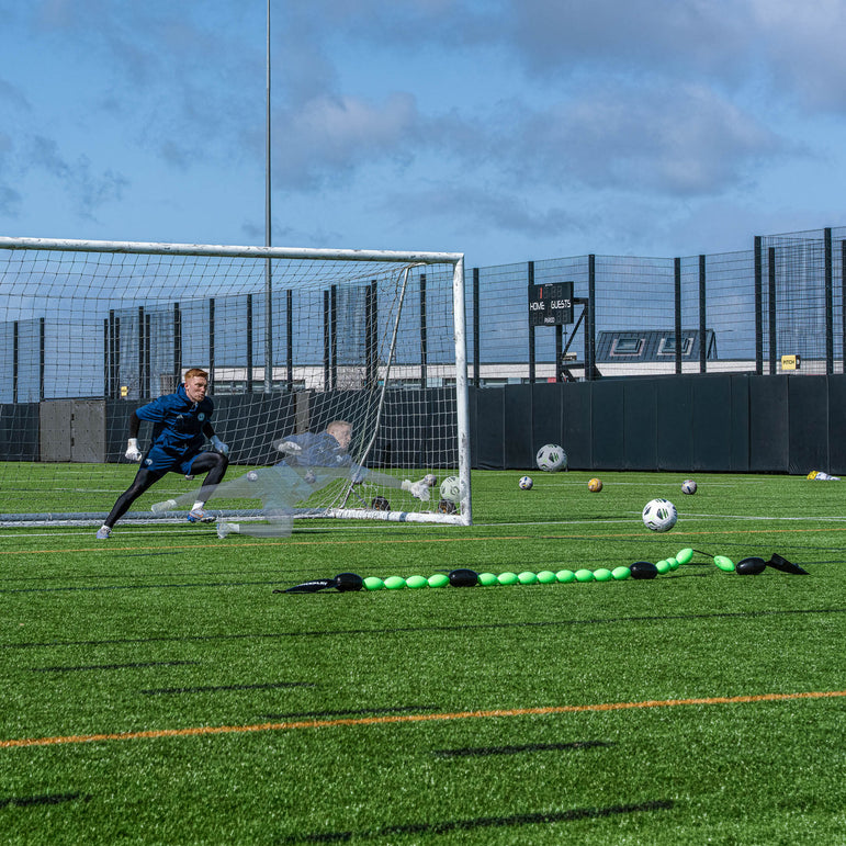 goalkeeper practicing soccer on a field with a goal and QUICKPLAY goalkeeper deflection line.