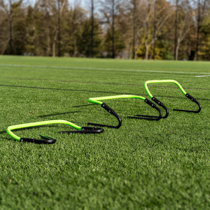 Set of green and black hurdles on a grass field with trees in the background