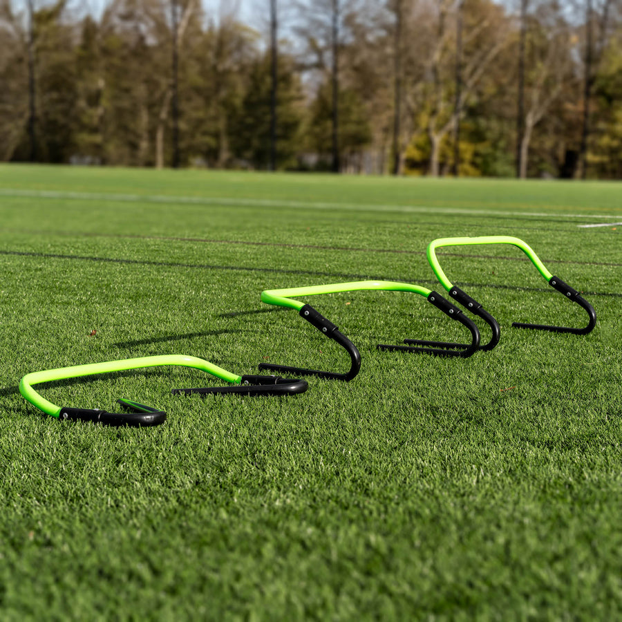 Set of green and black hurdles on a grass field with trees in the background