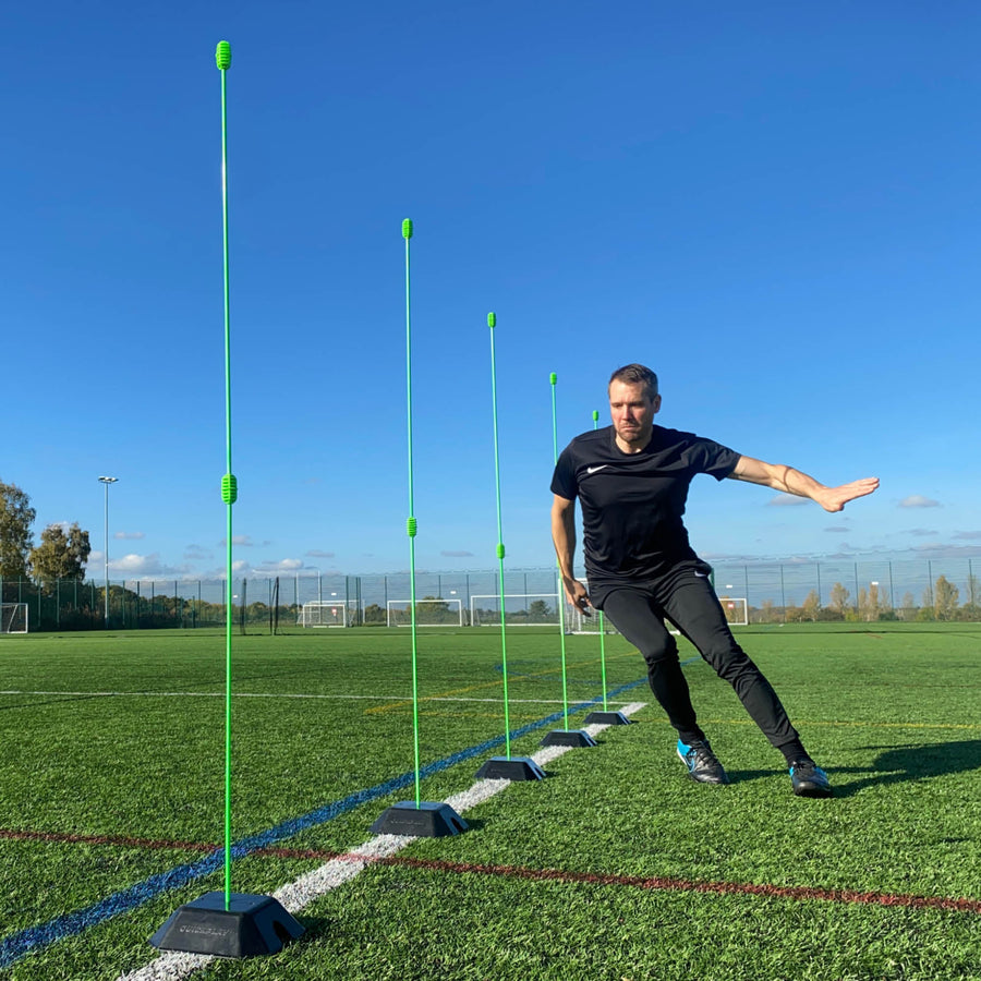Person practicing agility drills with green markers on a sports field