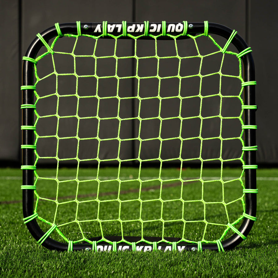 Handheld Rebounder front view, a black frame with a green net, standing on artificial grass.