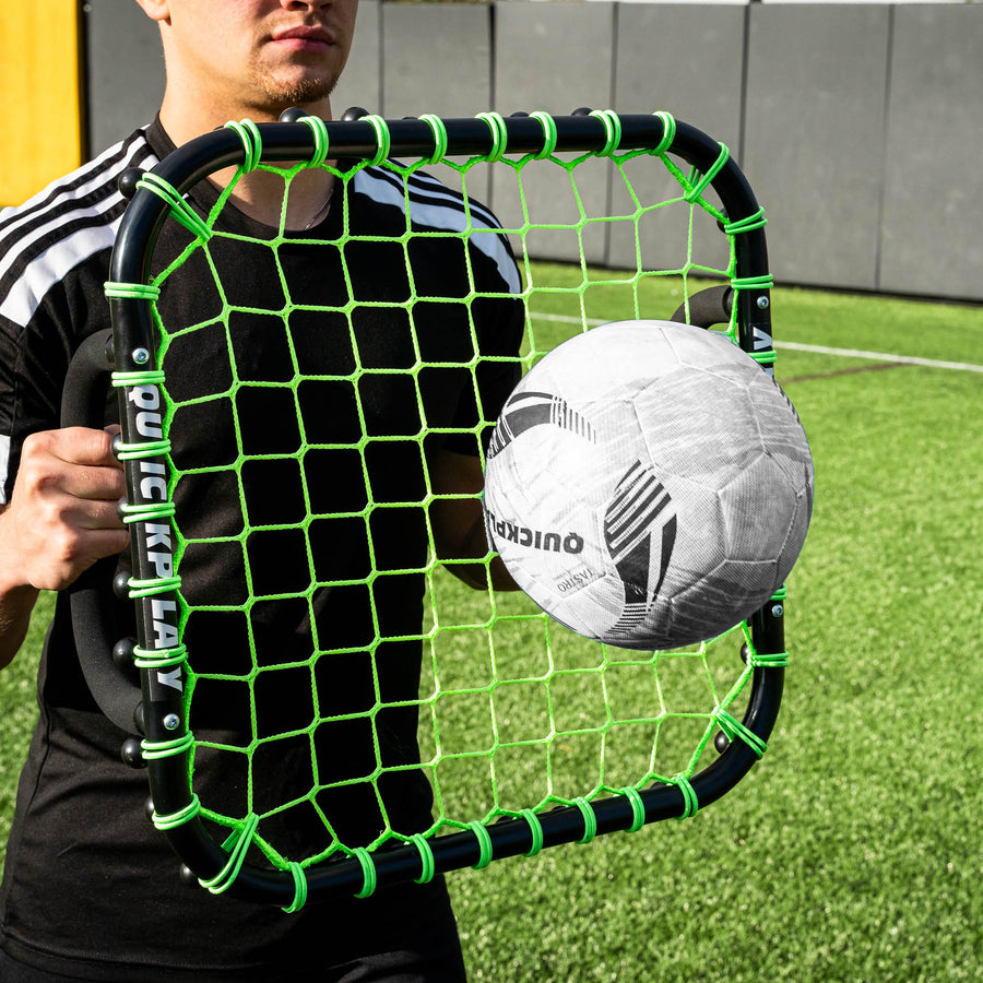 Player holding the Handheld Rebounder at chest height as a ball bounces off the green net.