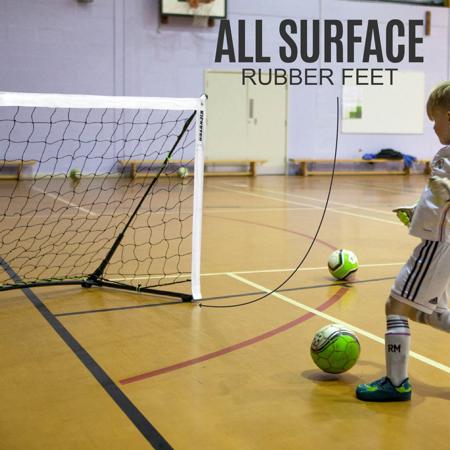 Child playing in a sports hall beside a KICKSTER Elite goal, with the text "All surface rubber feet".