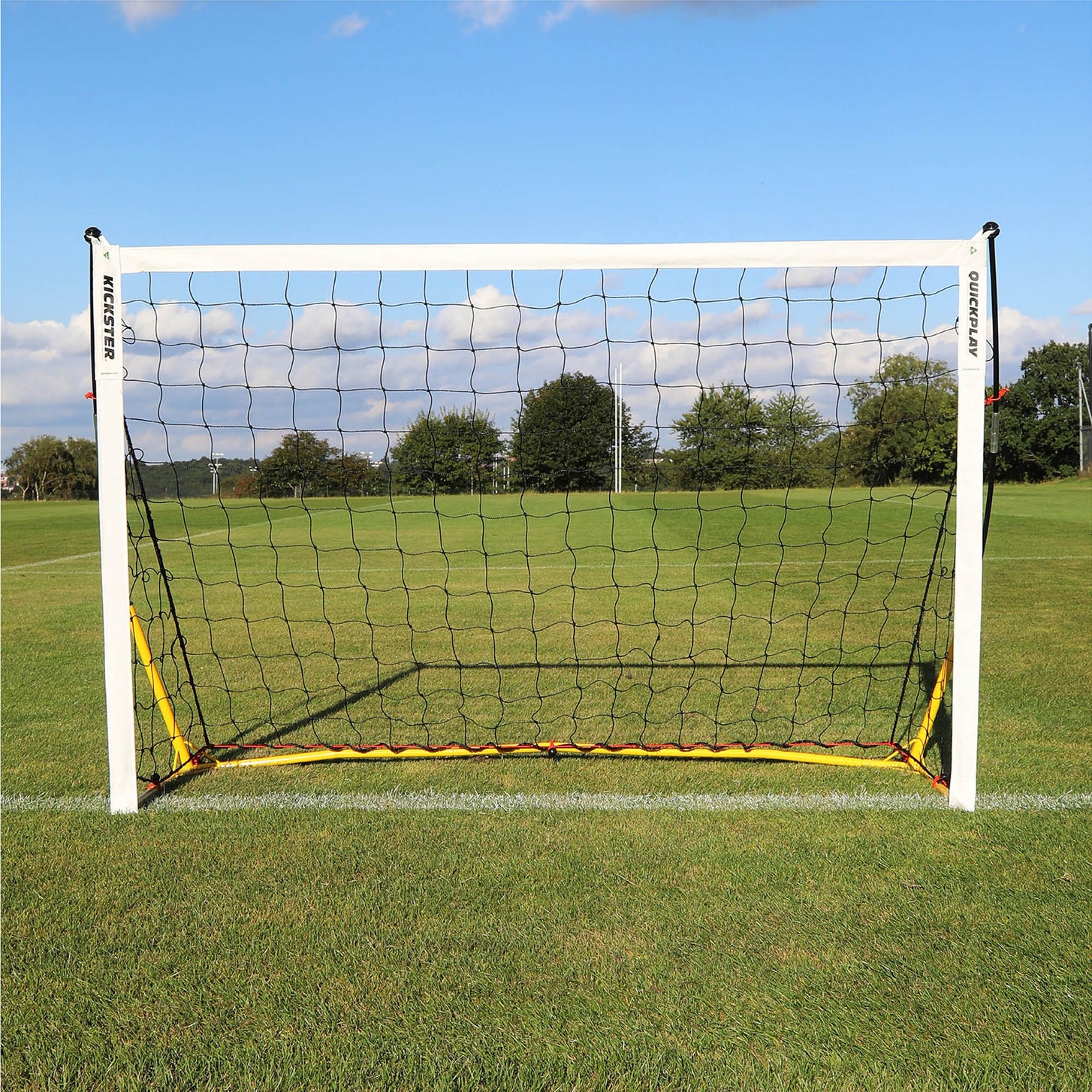 KICKSTER 6x4' (Yellow) goal from the front on a grass pitch, showing the yellow base bar and black net.