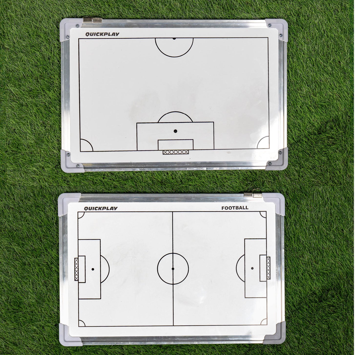 Two football coaching boards on grass with tactical diagrams.