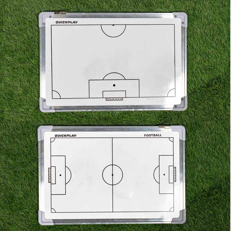 Two football coaching boards on grass with tactical diagrams.