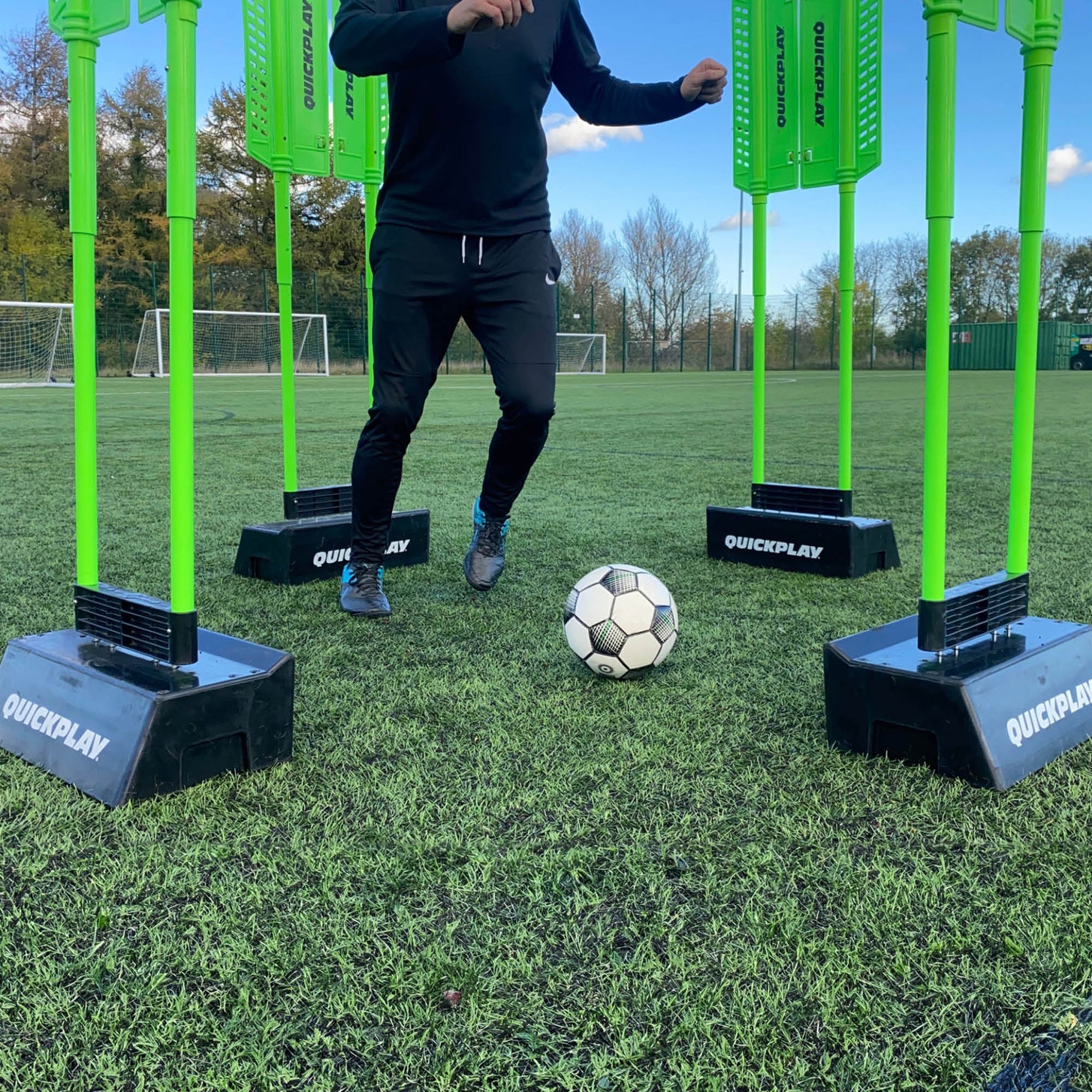Player dribbling a ball between green mannequins set in REPLAY Blocks on an artificial pitch.