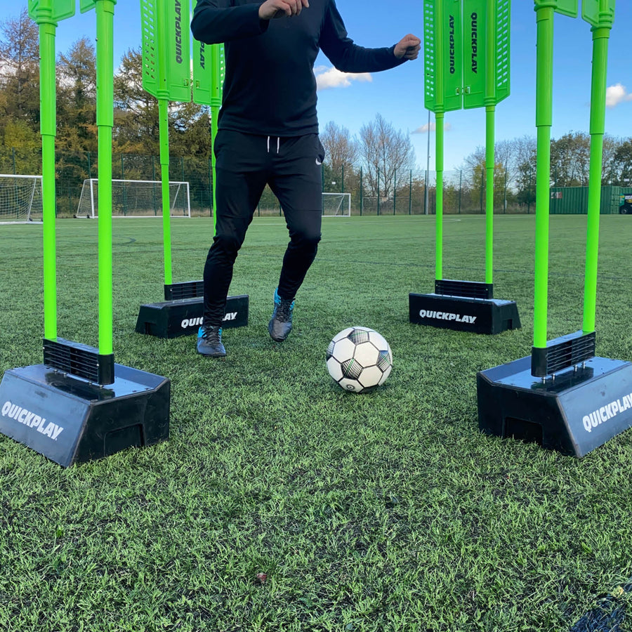 Player dribbling a ball between green mannequins set in REPLAY Blocks on an artificial pitch.