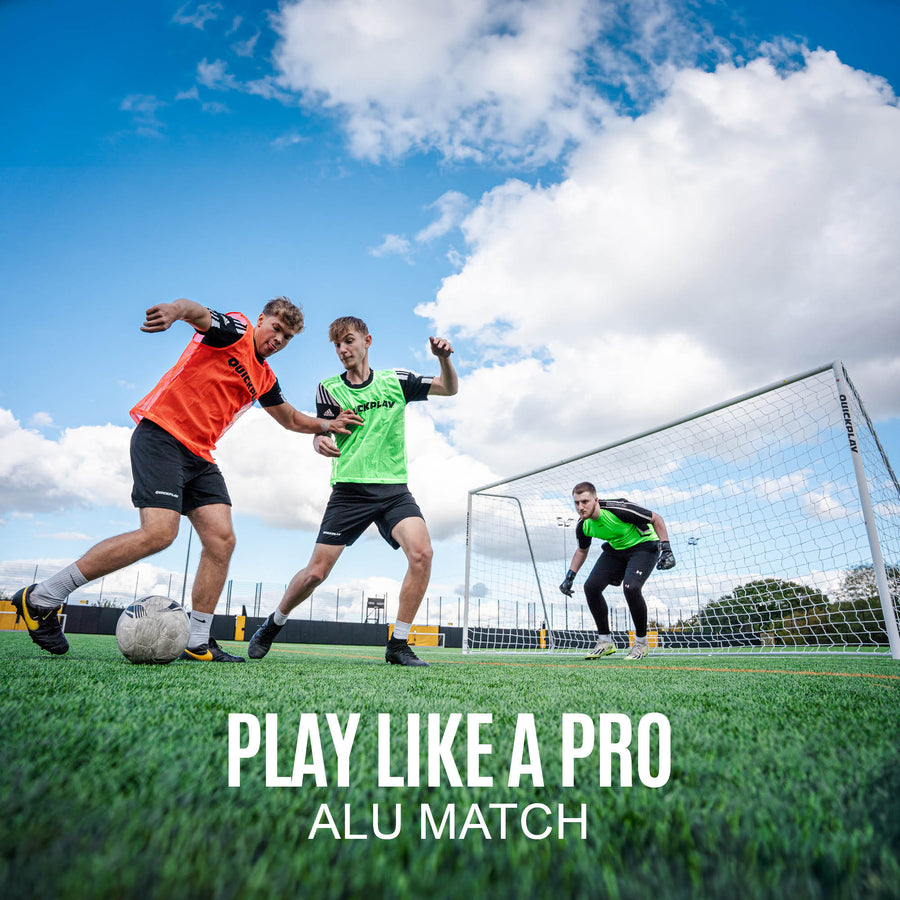 Two football players in action on a field with a goalkeeper, under a blue sky with clouds.