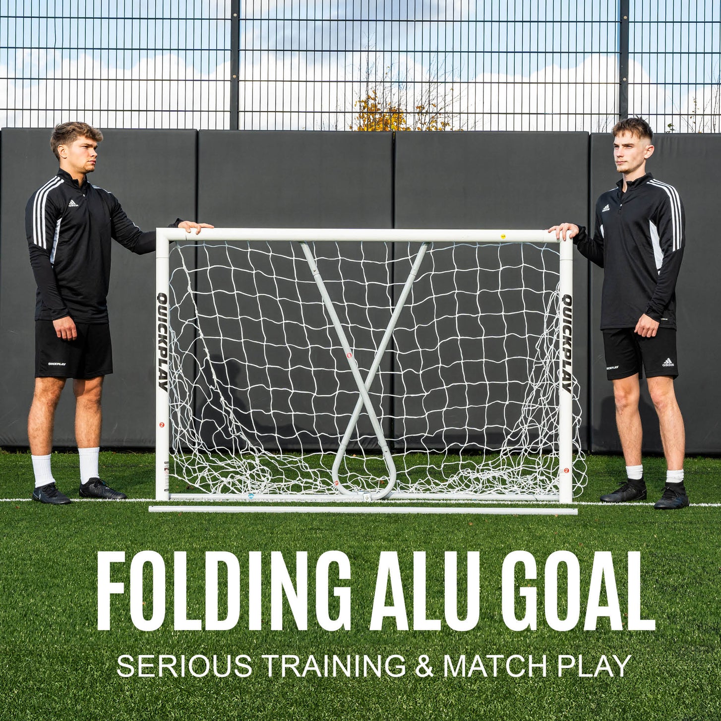 Two players holding the PRO ALU Match60 6x4' goal with its folding rear frame, with the text "Folding alu goal, serious training & match play".