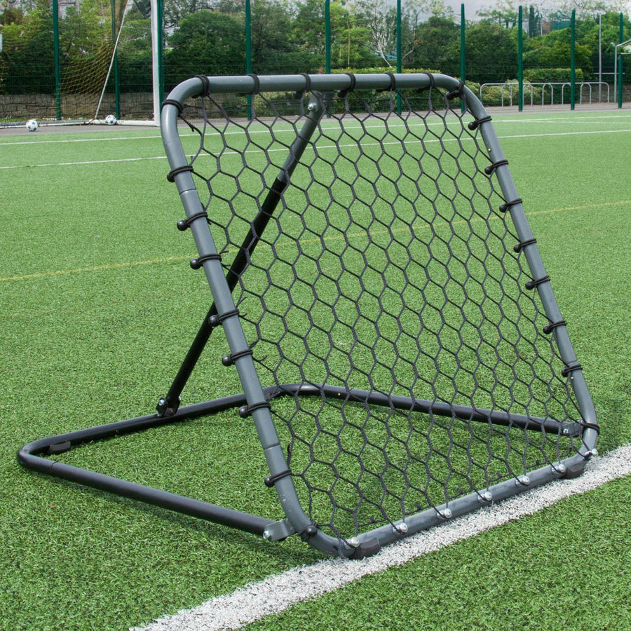 PRO Rebounder 3x3' with a grey frame and black hexagon net, standing at an angle on an artificial pitch.