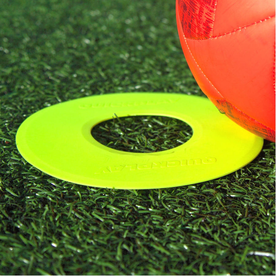 Single Flat Markers Neon yellow flat ring marker on artificial grass beside a red football.