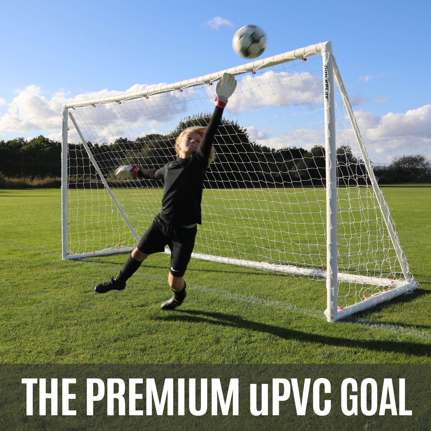 Person playing soccer with a goal and ball on a grassy field