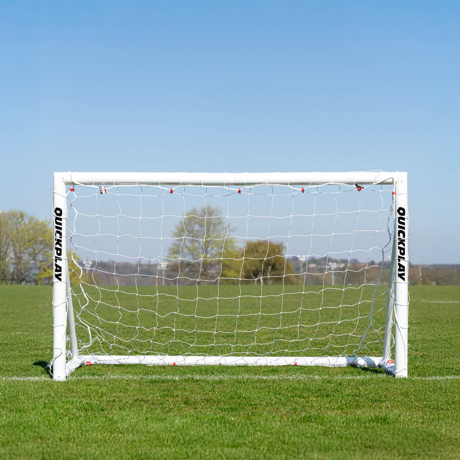 Soccer goal with 'QuickPlay' branding on a grass field under a clear blue sky.