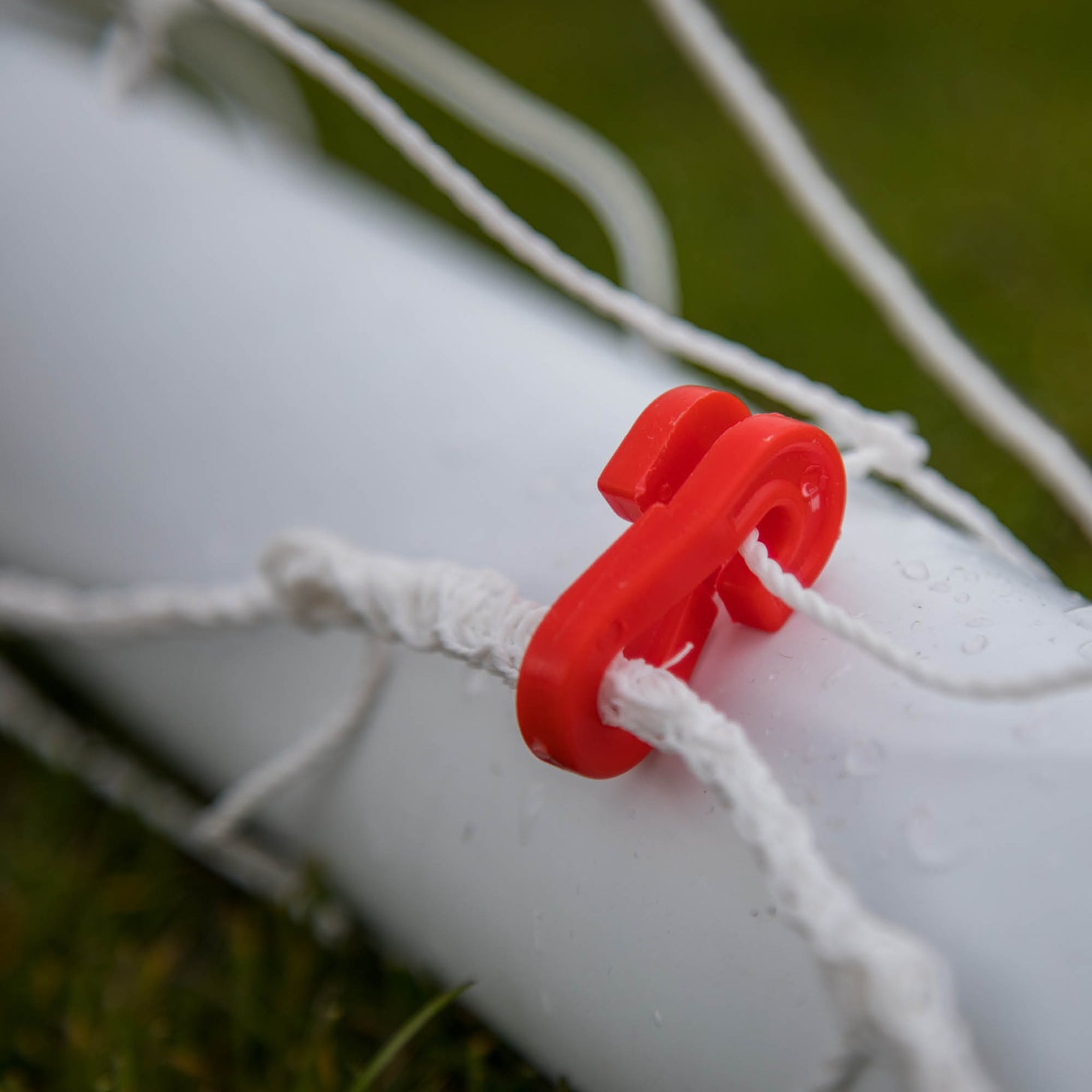 Close-up of a red plastic clip holding the net to the white frame of the Q-FOLD Mini 3x2.5'.