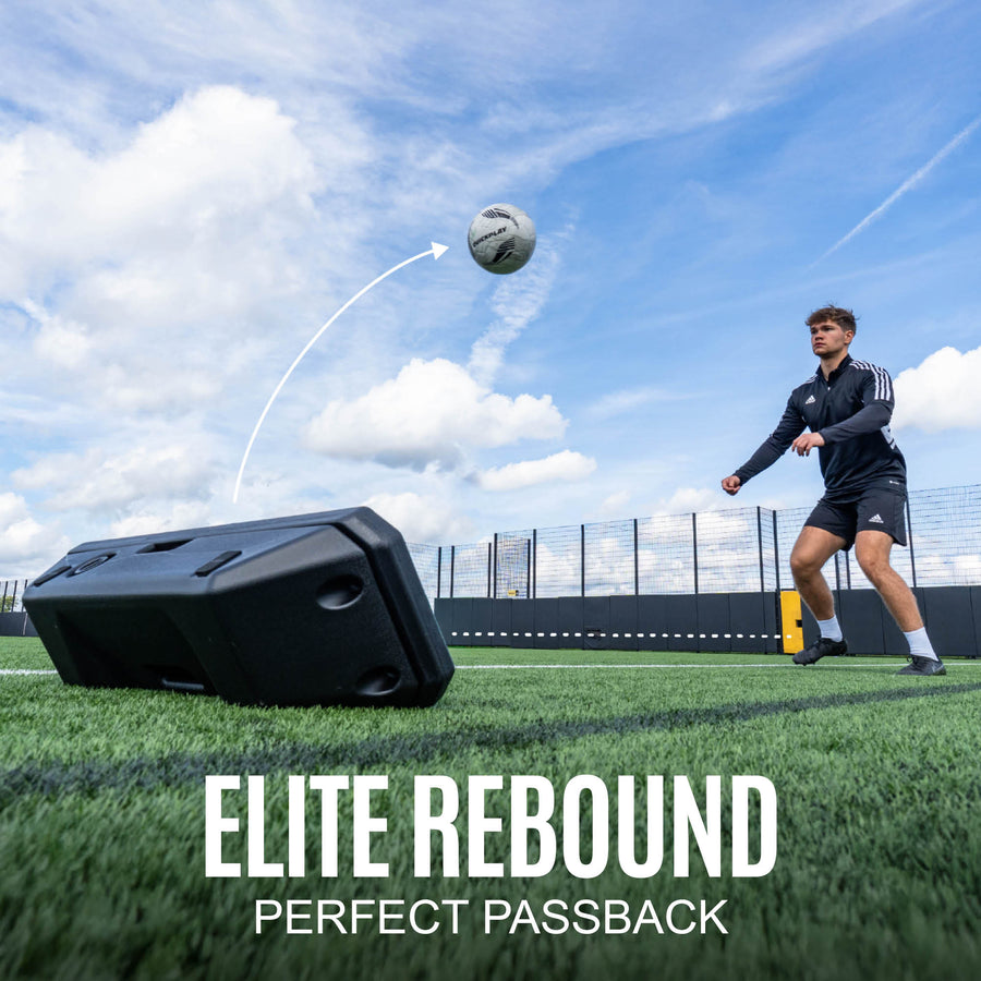 Person practicing football passbacks with a rebounder on a sports field.