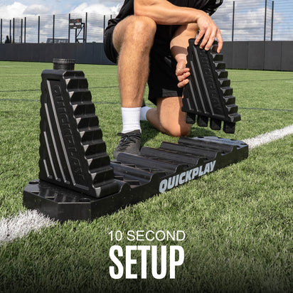 Person using a QuickPlay football rebound board on a grass field