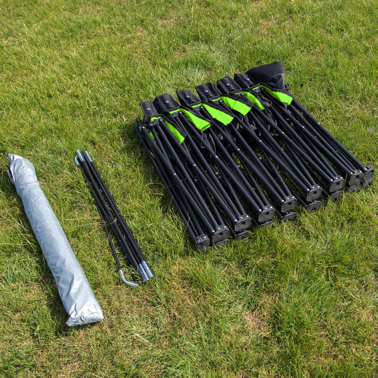 PRO Bench Shelter packed down on grass: the folded seat frame, canopy poles and rolled grey canopy.