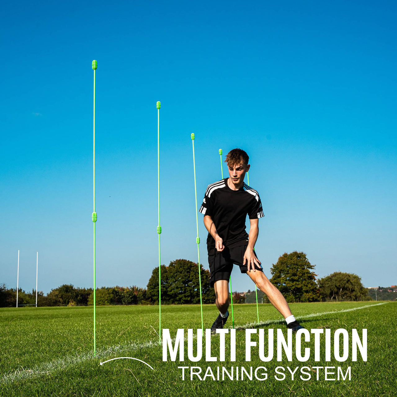 Person using a multi-function training system on a grass field with clear blue sky