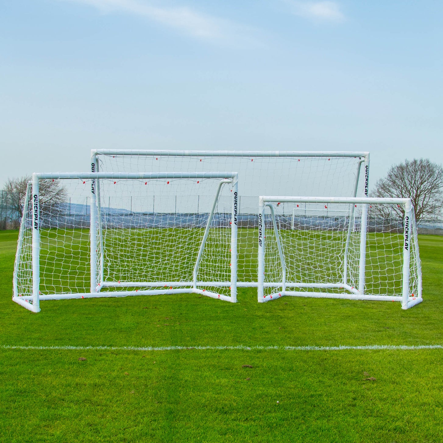Q-FOLD Match 8x5' goal shown with two other white QUICKPLAY goals of different sizes on a grass pitch.