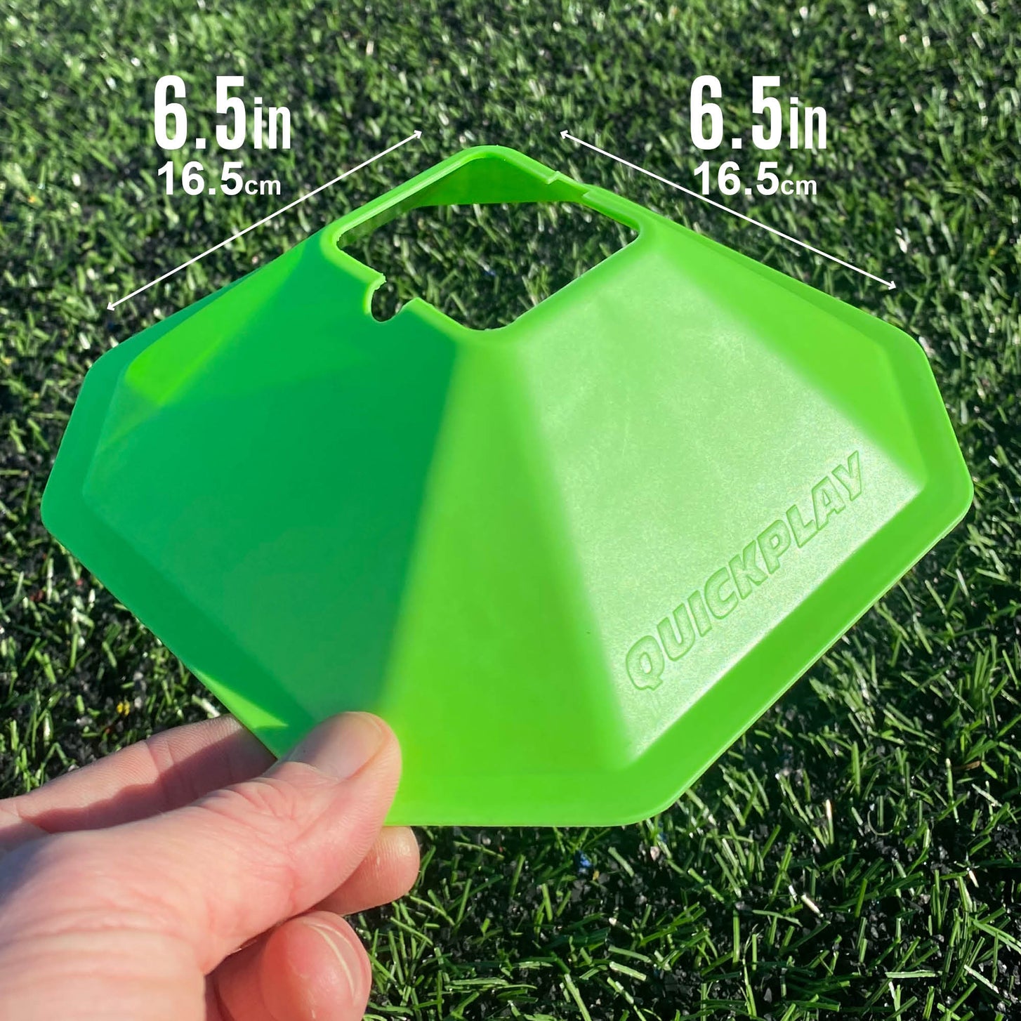 Hand holding a green Standard Cone over artificial grass, marked 16.5cm (6.5in) along two of its sides.