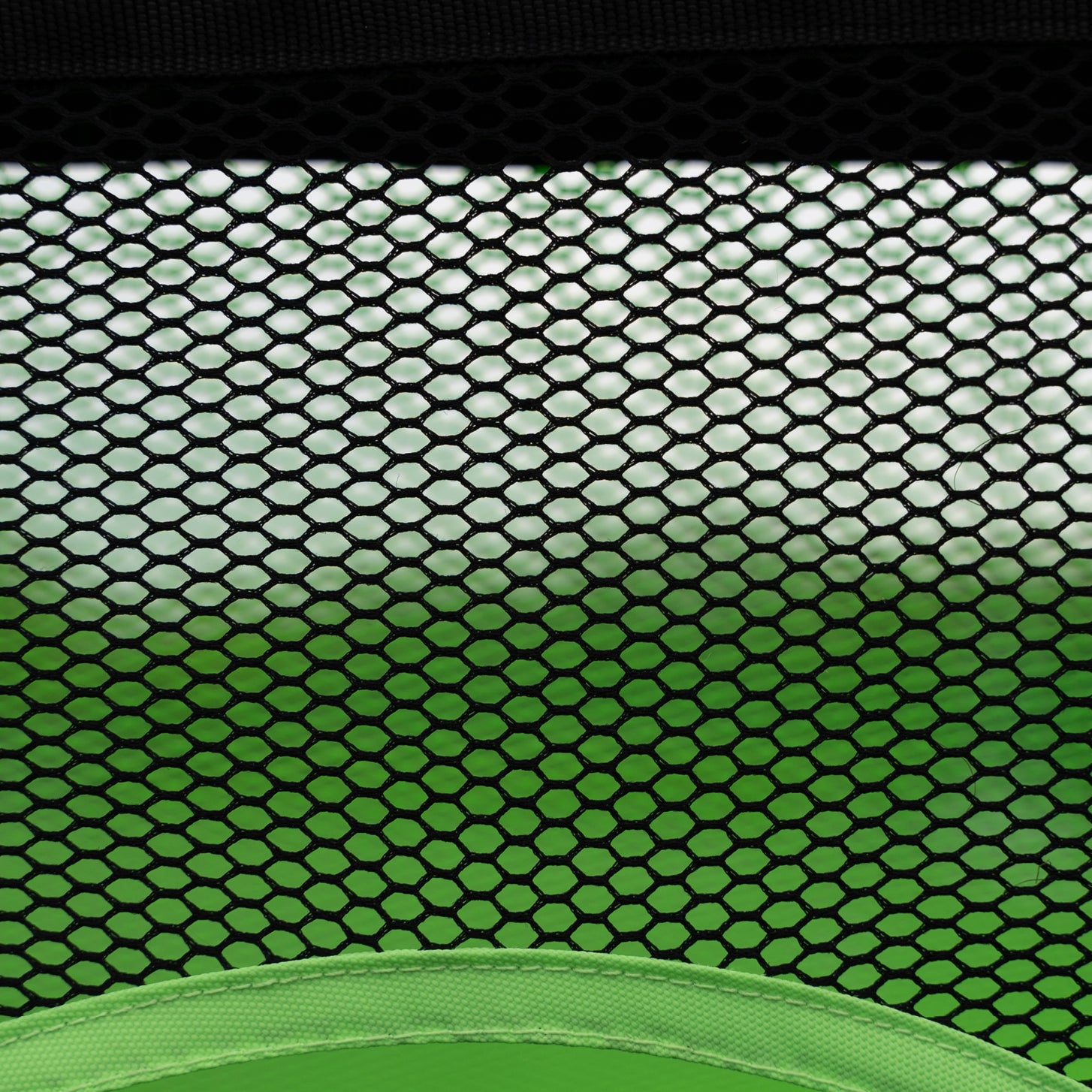 Close up of the black mesh of the PRO ALU Training Target Net Lite 6x4' above the green edge of a target hole.