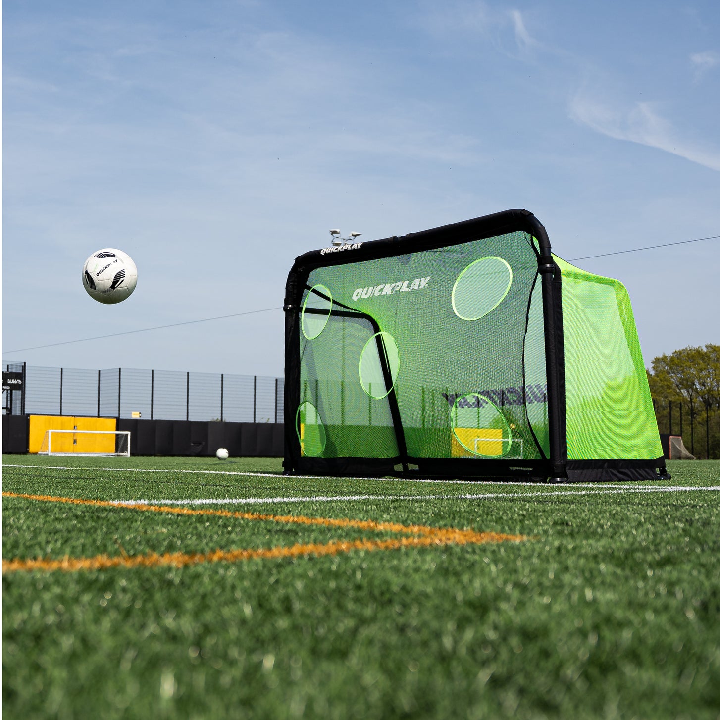 Low angle view of a ball in the air near the PRO ALU Training Target Net Lite 6x4' fitted to a goal on an artificial pitch.