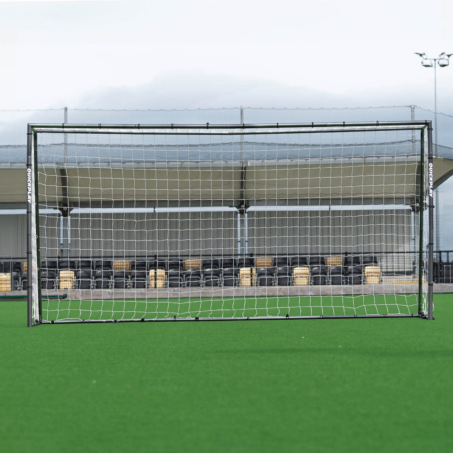 GS Series Football Goal 12x6' seen straight on in front of a covered stand with a floodlight behind.