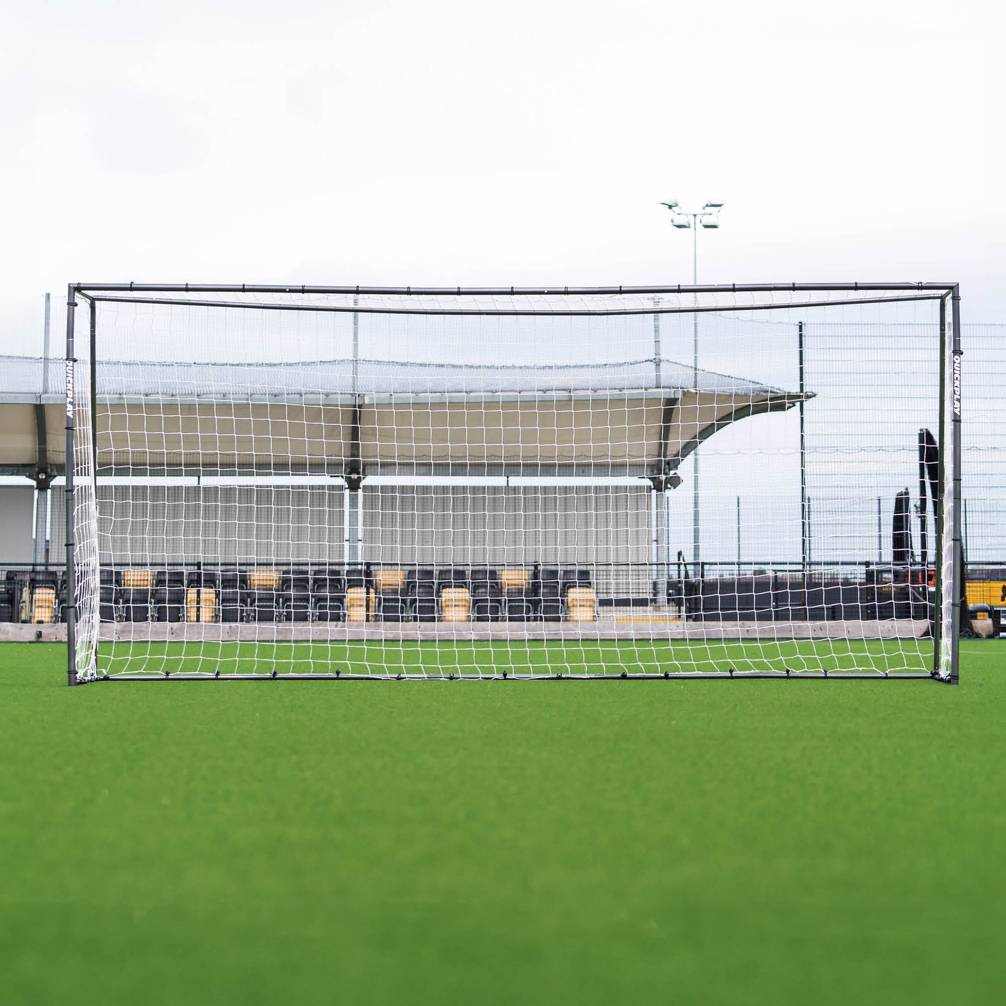 GS Series Football Goal 16x7' seen straight on in front of a covered stand on an artificial pitch.