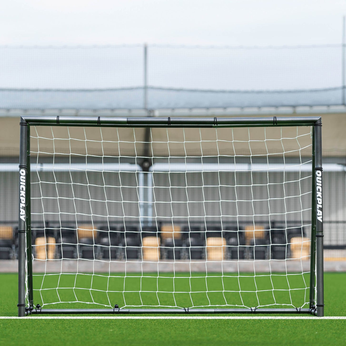 GS Series Football Goal 6x4' seen straight on in front of a stadium stand, with QUICKPLAY printed on both posts.