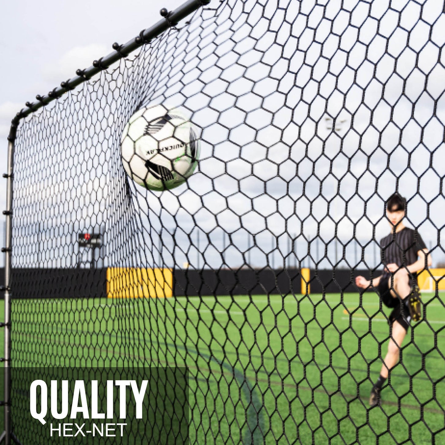 Ball hitting the black hex net of the Barrier Net & Rebounder 12x6' as a player kicks, with the text "Quality hex-net".