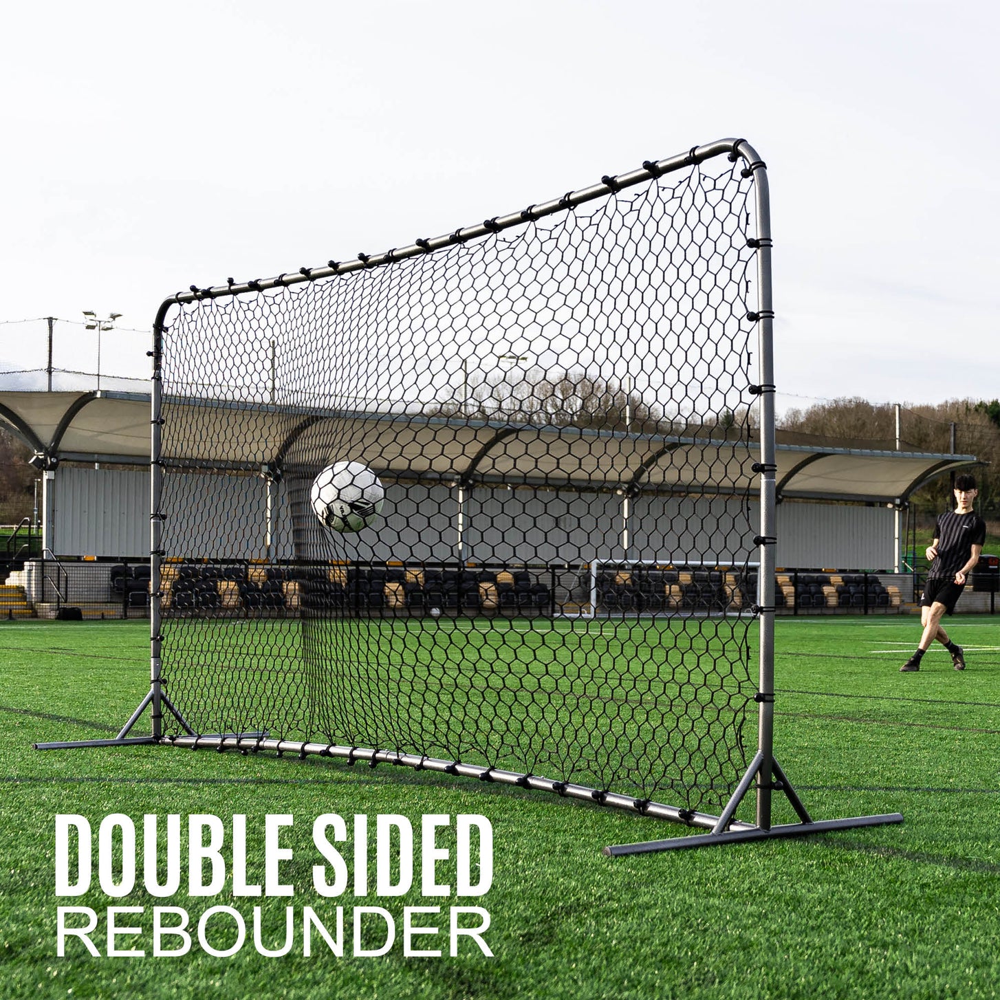 Ball bouncing off the Barrier Net & Rebounder 12x6' towards a player on artificial grass, with the text "Double sided rebounder".