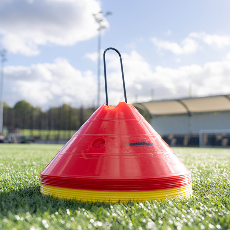 Red and yellow sports marker cone on a grass field with a blurred background