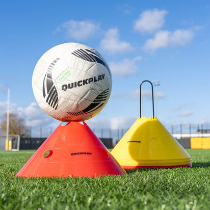 Quickplay soccer ball on a red cone with a yellow marker on a grass field