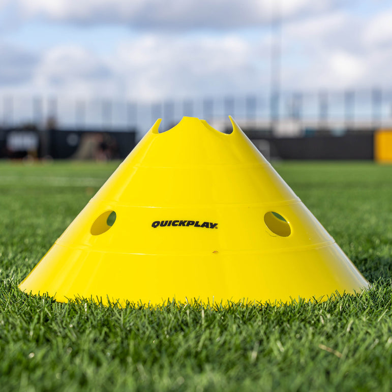 Yellow training cone with 'QuickPlay' branding on a grass field